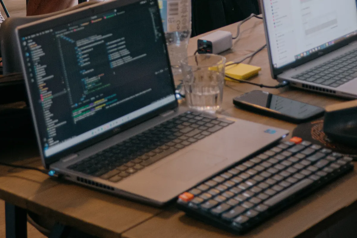 A laptop showing code on a desk beside a second screen during the WealthArc hackathon