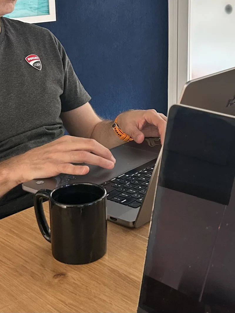 A colleague working at a laptop with a coffee beside them